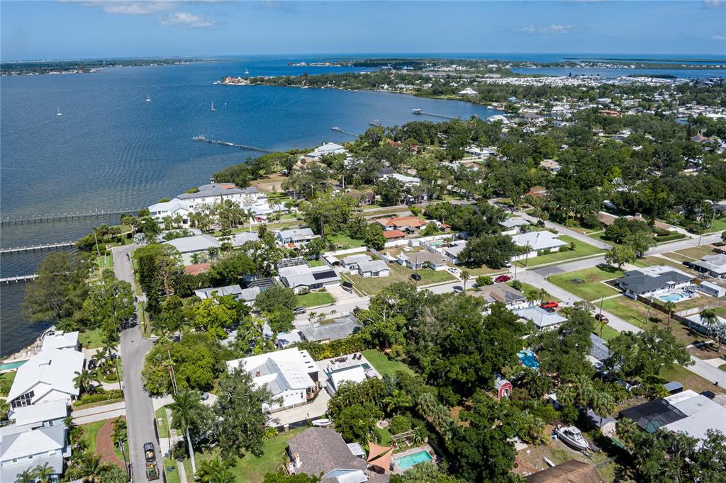 An aerial view shows a coastal neighborhood with houses, lush trees, and a large bay — 415 20TH AVENUE W, PALMETTO, FL