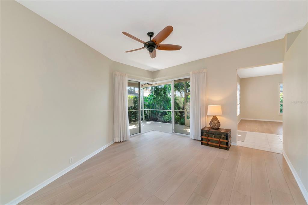 A living room with light wood flooring, a ceiling fan, and sliding glass doors to a patio — 309 AMERICAS CUP BOULEVARD, BRADENTON, FL
