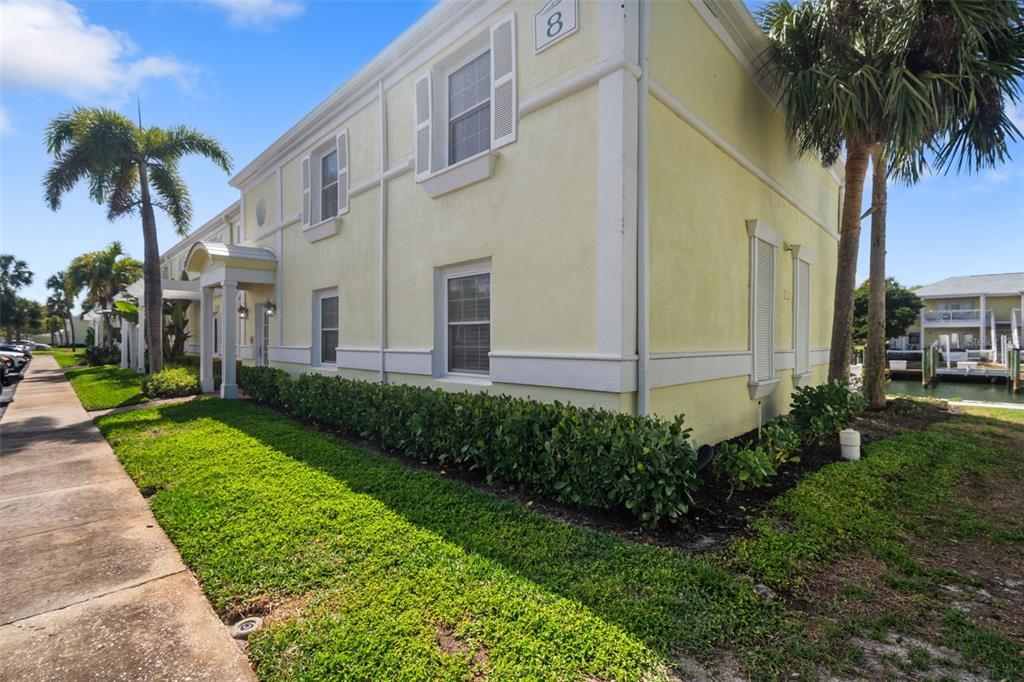 A two-story yellow apartment building with white trim sits next to a sidewalk and canal — 4911 COQUINA KEY DRIVE SE UNIT C, ST PETERSBURG, FL