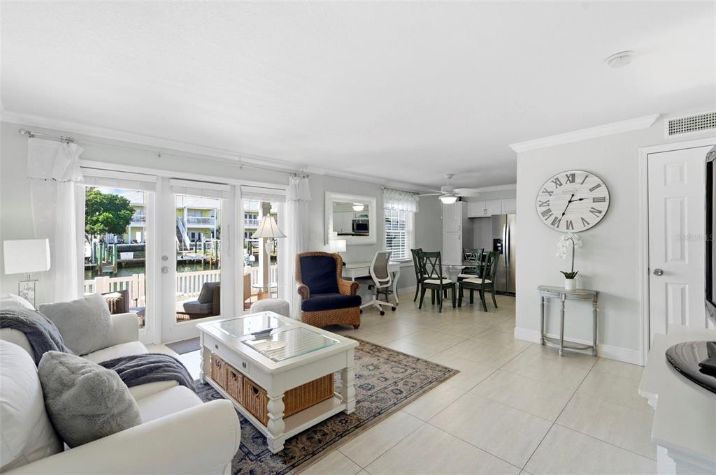 A bright living and dining area features tile floors, a white coffee table, and waterfront views — 4911 COQUINA KEY DRIVE SE UNIT C, ST PETERSBURG, FL