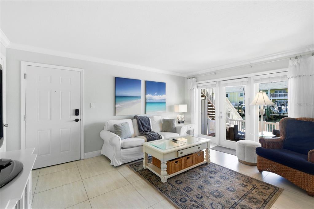 A living room features a white sofa, a coffee table, and sliding doors overlooking a marina — 4911 COQUINA KEY DRIVE SE UNIT C, ST PETERSBURG, FL