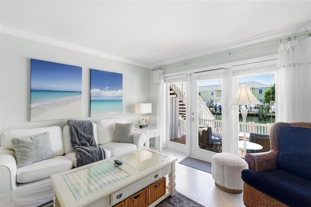 A living room with white furniture, a glass-topped coffee table, and a view of boats — 4911 COQUINA KEY DRIVE SE UNIT C, ST PETERSBURG, FL
