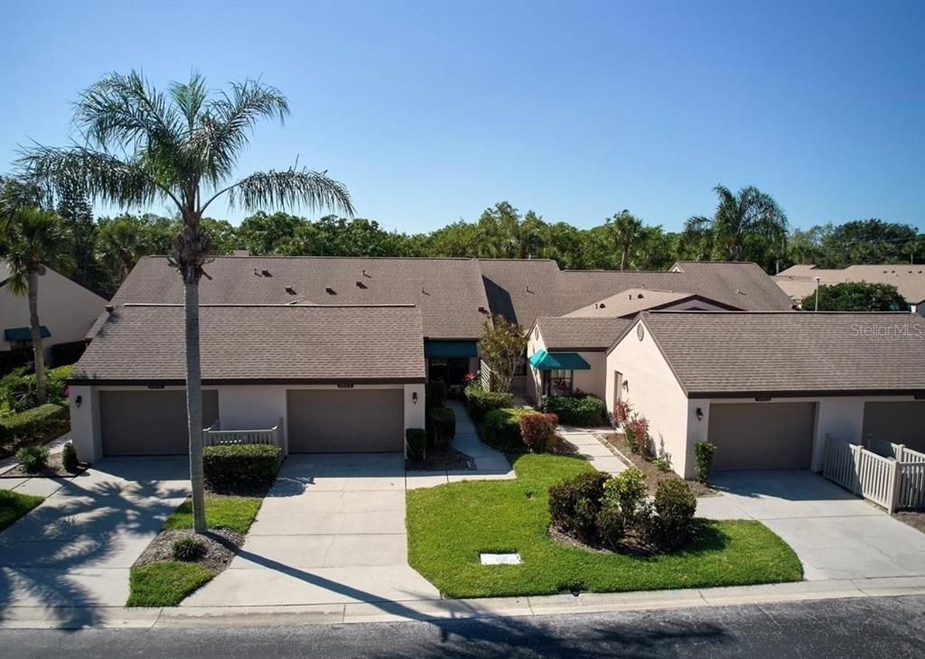 An exterior view of a multi-unit residential building with attached garages and a palm tree — 5924 CLUBSIDE DRIVE, SARASOTA, FL