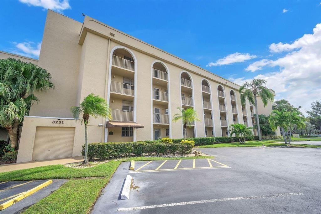 A multi-story beige apartment building features arched balconies and a ground-level parking lot — 3231 Holiday Springs Boulevard # 105, Margate FL 33063, MARGATE, FL