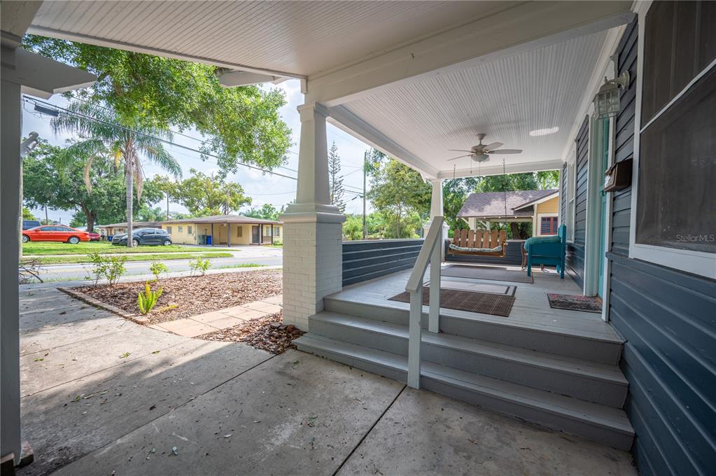 A covered front porch features wooden steps, a ceiling fan, and a hanging porch swing — 817 E LIME STREET, LAKELAND, FL