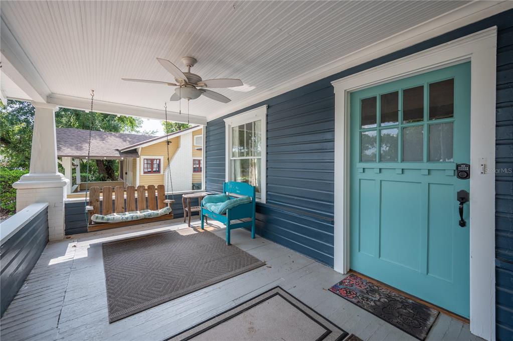 A covered front porch features a wooden swing, a blue bench, and a turquoise door — 817 E LIME STREET, LAKELAND, FL