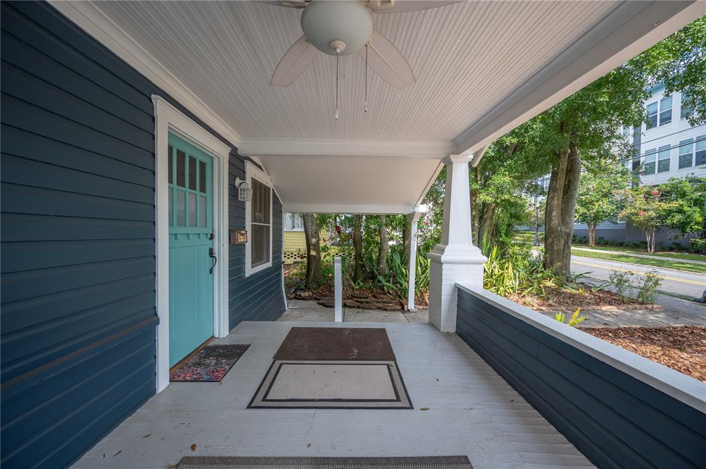 A covered front porch with blue siding, a teal door, and a ceiling fan — 817 E LIME STREET, LAKELAND, FL