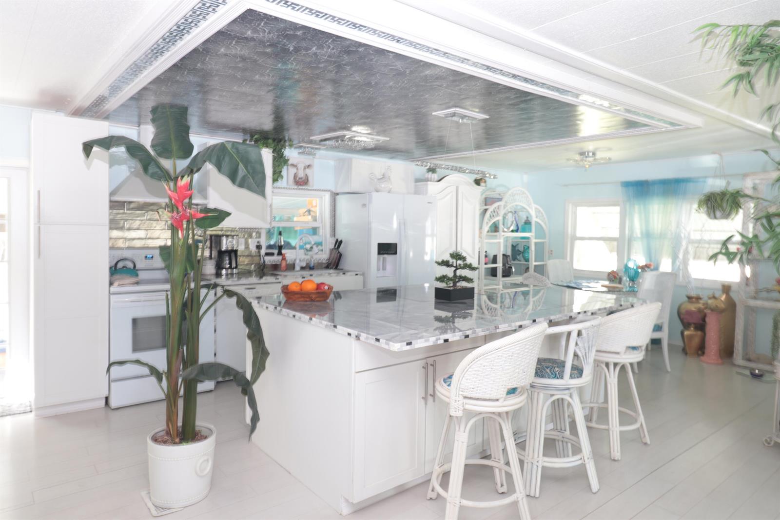 A kitchen features a large marble-topped island, white cabinetry, and a metallic coffered ceiling — 1011 Andros, Boynton Beach FL 33436, BOYNTON BEACH, FL