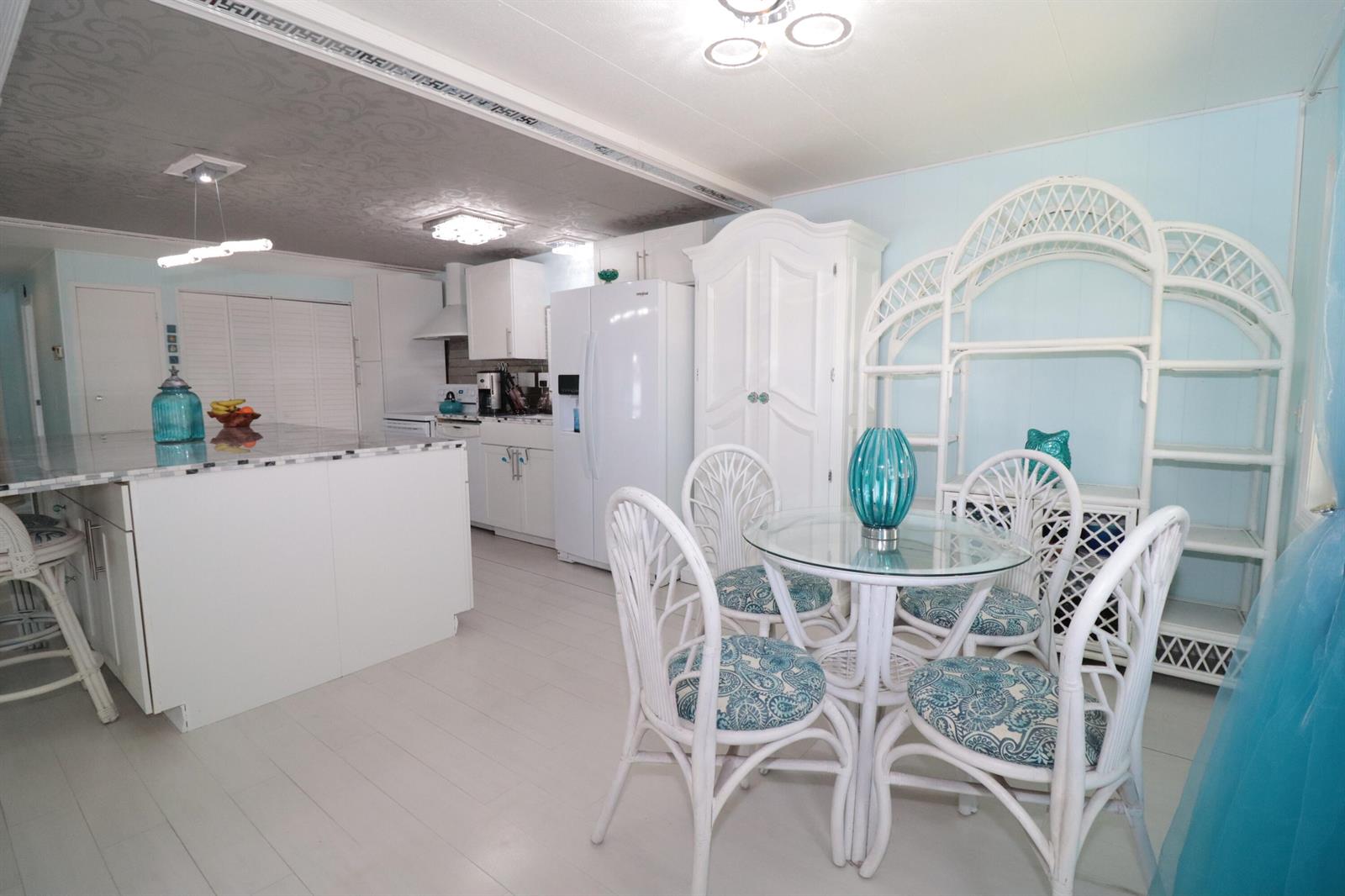 A bright kitchen and dining area features white cabinetry, a center island, and wicker furniture — 1011 Andros, Boynton Beach FL 33436, BOYNTON BEACH, FL