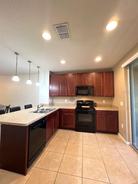 A kitchen with dark wood cabinets, granite countertops, black appliances, and tile flooring — 1162 CHELSEA DRIVE, DAVENPORT, FL
