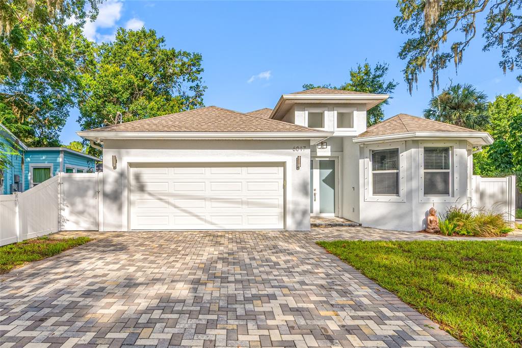 A single-story house with a white stucco exterior, a two-car garage, and a paver driveway — 6017 ADAMS STREET, NEW PORT RICHEY, FL