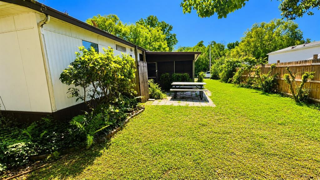 A backyard features a white mobile home, a patio with a picnic table, and fencing — 4228 ATHENS AVENUE, NEW PORT RICHEY, FL
