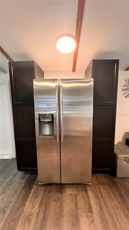 A stainless steel refrigerator is positioned between two dark wood floor-to-ceiling cabinets — 4228 ATHENS AVENUE, NEW PORT RICHEY, FL