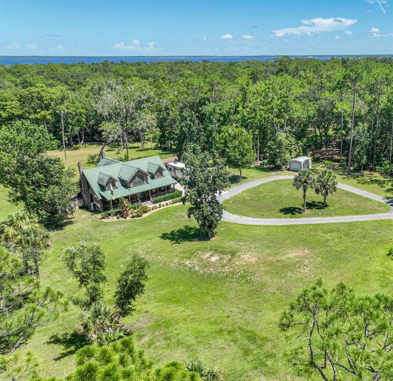 An aerial view shows a house on a large, wooded lot outlined in yellow — 1223 SUTTON TRAIL, GENEVA, FL