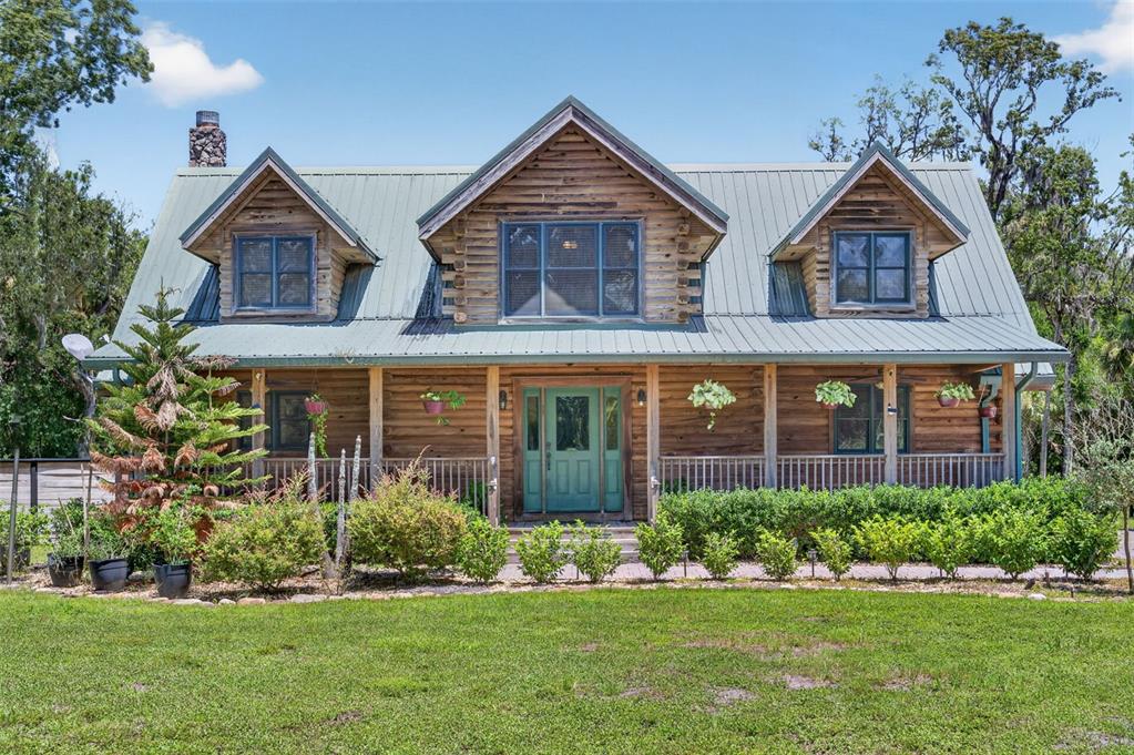 An aerial view shows a green-roofed house with a circular driveway on a wooded lot — 1223 SUTTON TRAIL, GENEVA, FL