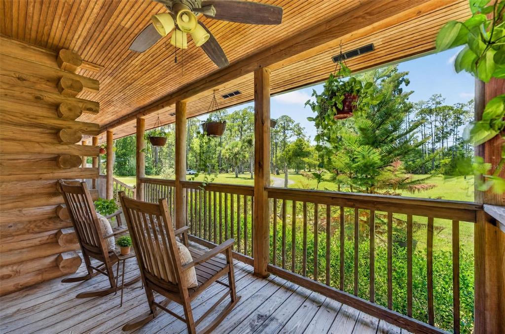 A two-story log cabin home features a metal roof, three dormers, and a front porch — 1223 SUTTON TRAIL, GENEVA, FL