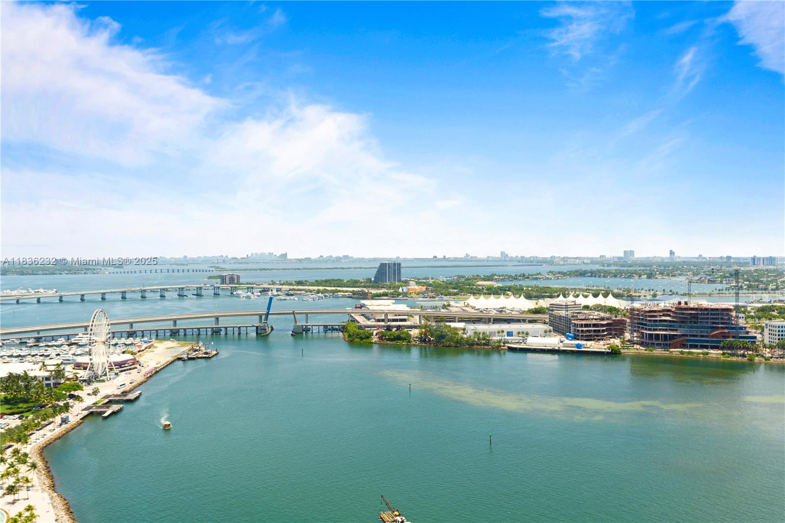 An aerial view shows a bridge, a marina with a ferris wheel, and coastal buildings — 335 S Biscayne Blvd # 3410, Miami FL 33131, MIAMI, FL
