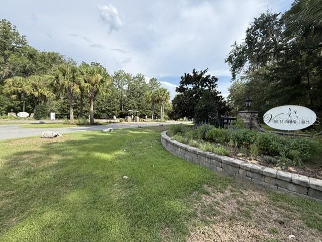 A stone retaining wall borders a grassy lawn leading to the entrance of a neighborhood — 0 NW 148 LANE, REDDICK, FL