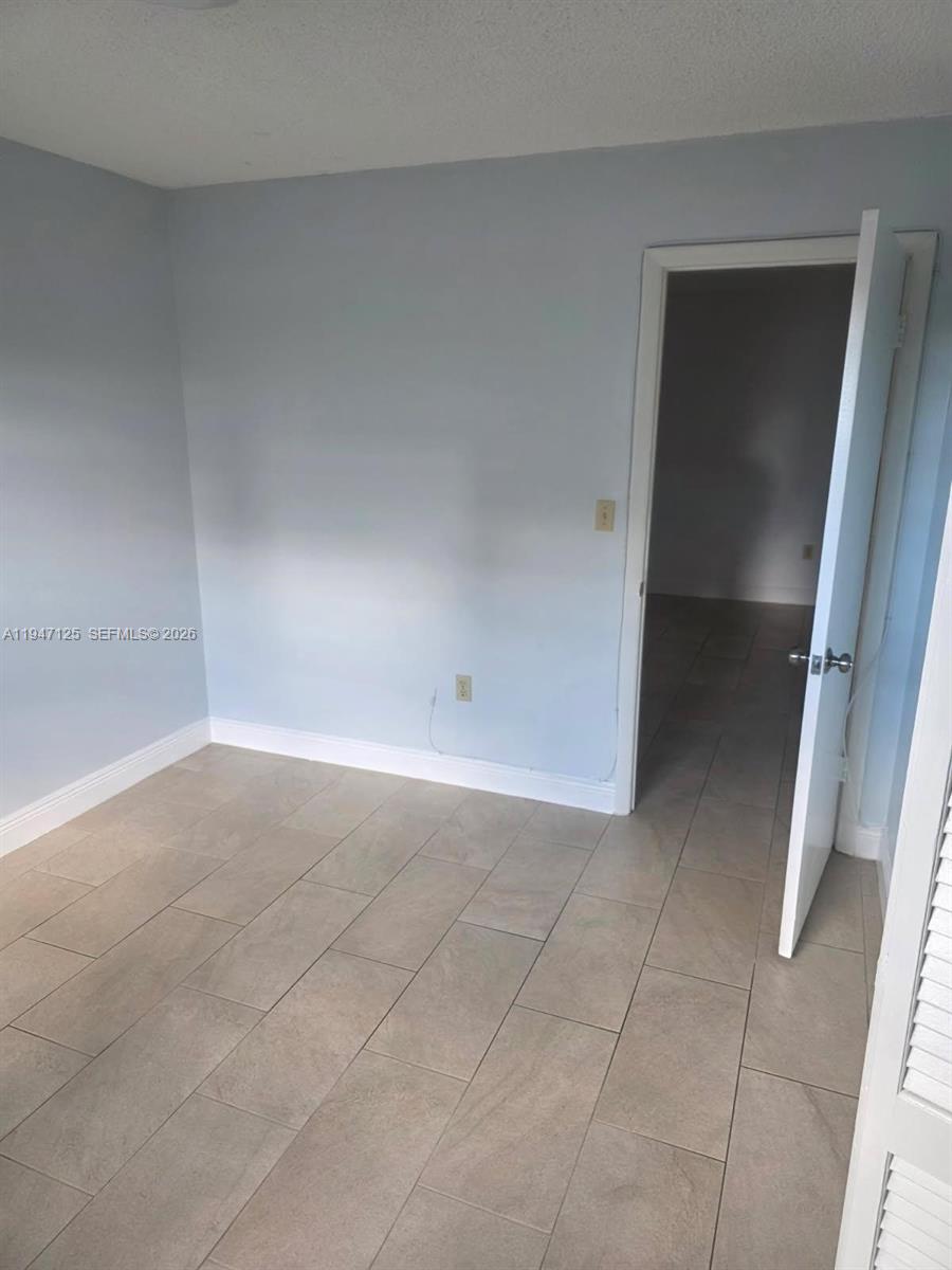 A room with light blue walls, tan tile flooring, and an open doorway — 1575 NW 1st ST # 3, Miami FL 33125, MIAMI, FL