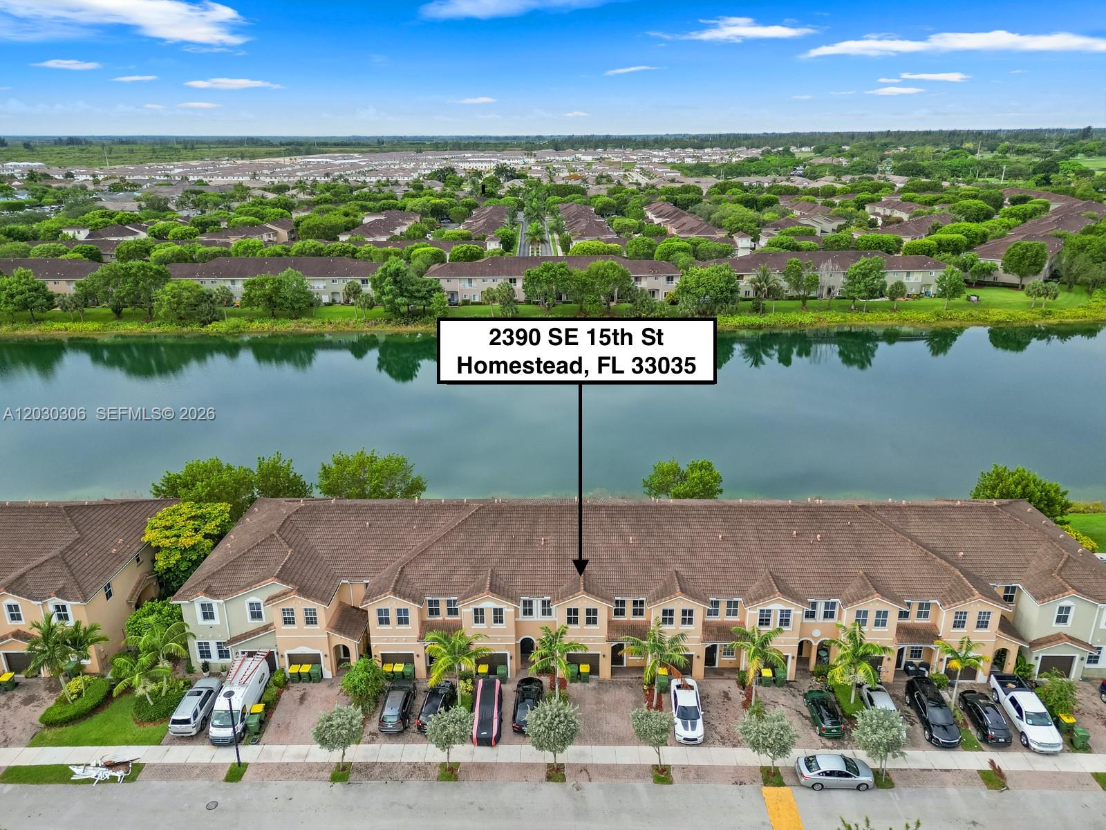 An aerial view shows a row of townhouses situated along a lake — 2390 SE 15th St, Homestead FL 33035, HOMESTEAD, FL