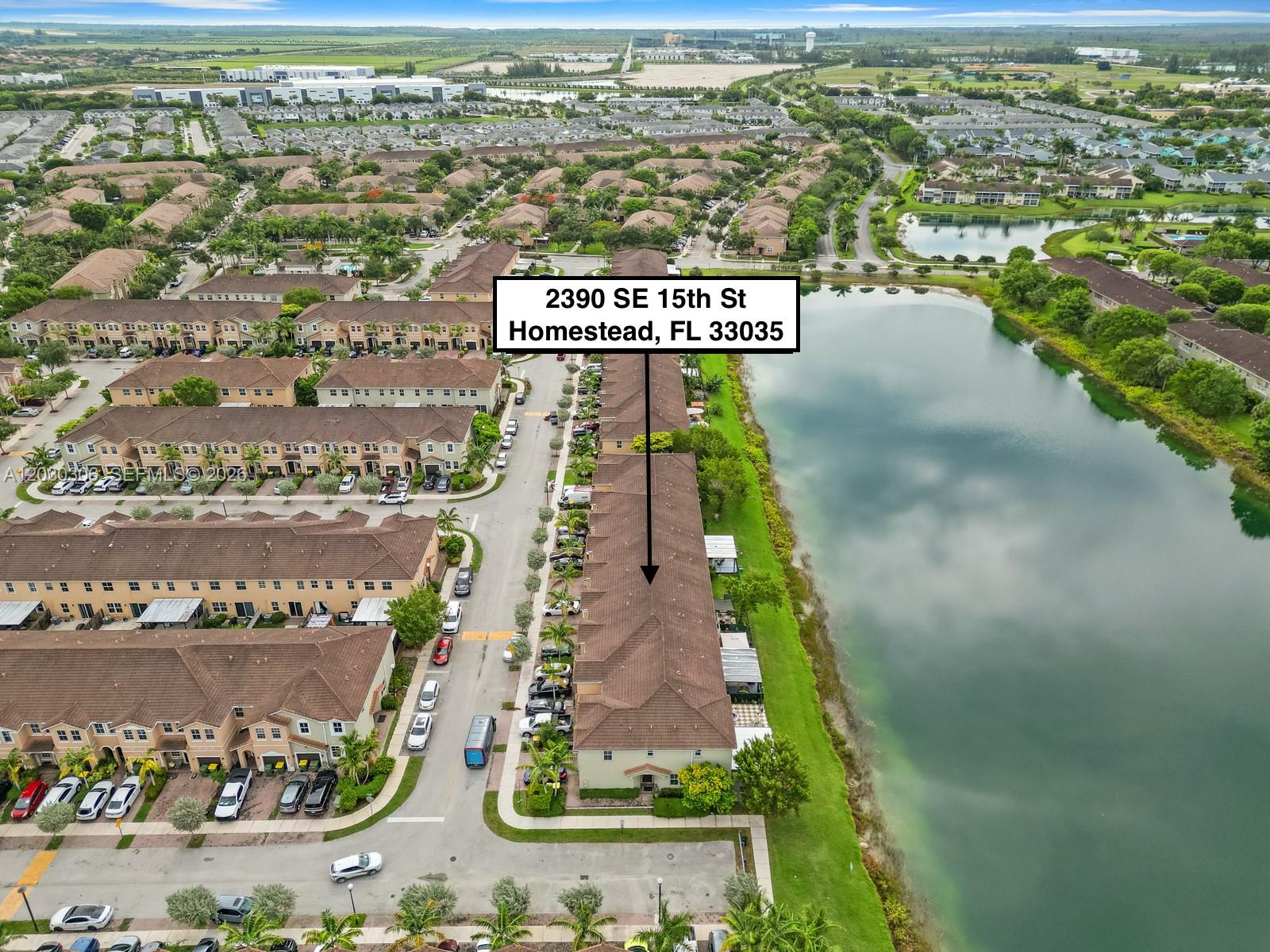 An aerial view shows a row of townhouses situated next to a large lake — 2390 SE 15th St, Homestead FL 33035, HOMESTEAD, FL