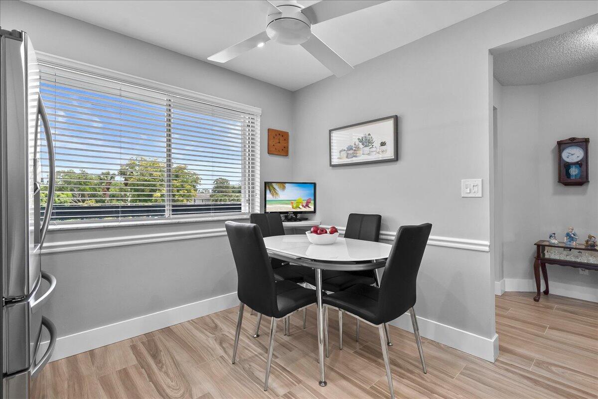 A dining area features a white table with four black chairs and light wood flooring — 6698 10th Avenue N # 305, Lake Worth FL 33461, LAKE WORTH, FL