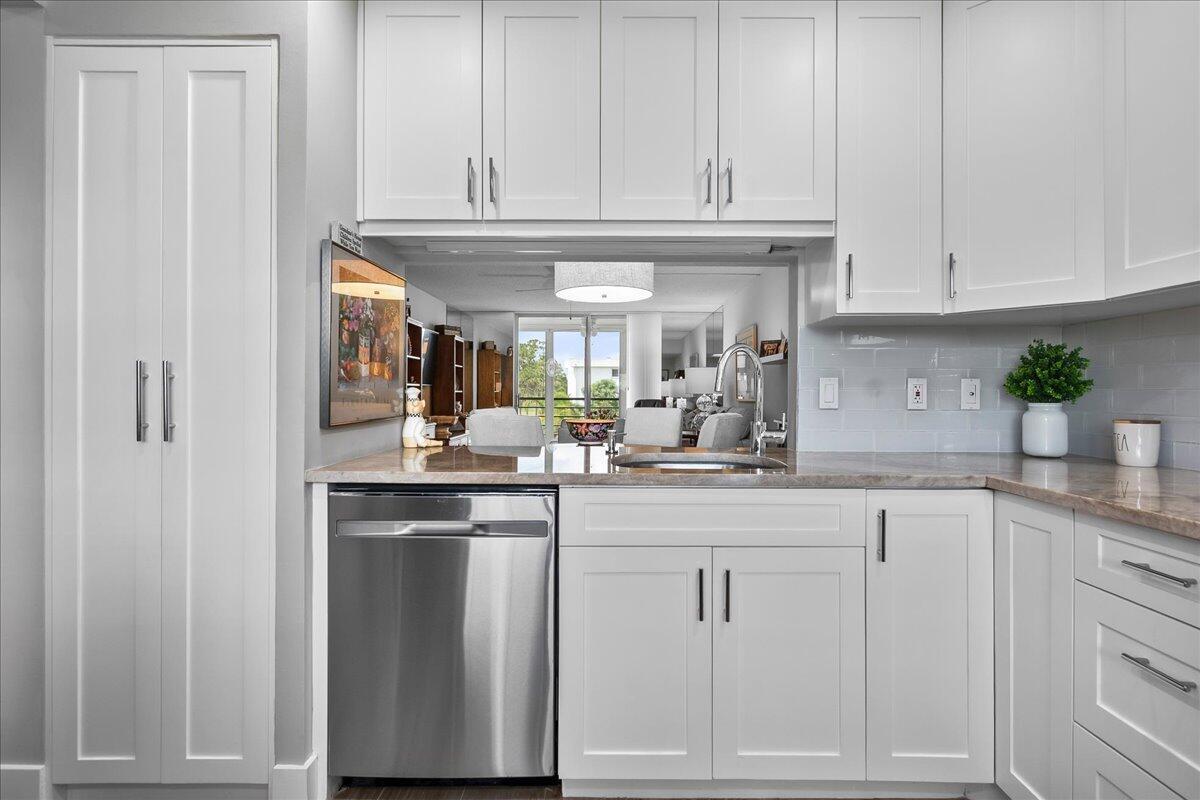 A kitchen features white cabinets, stainless steel appliances, and a pass-through window to the living area — 6698 10th Avenue N # 305, Lake Worth FL 33461, LAKE WORTH, FL