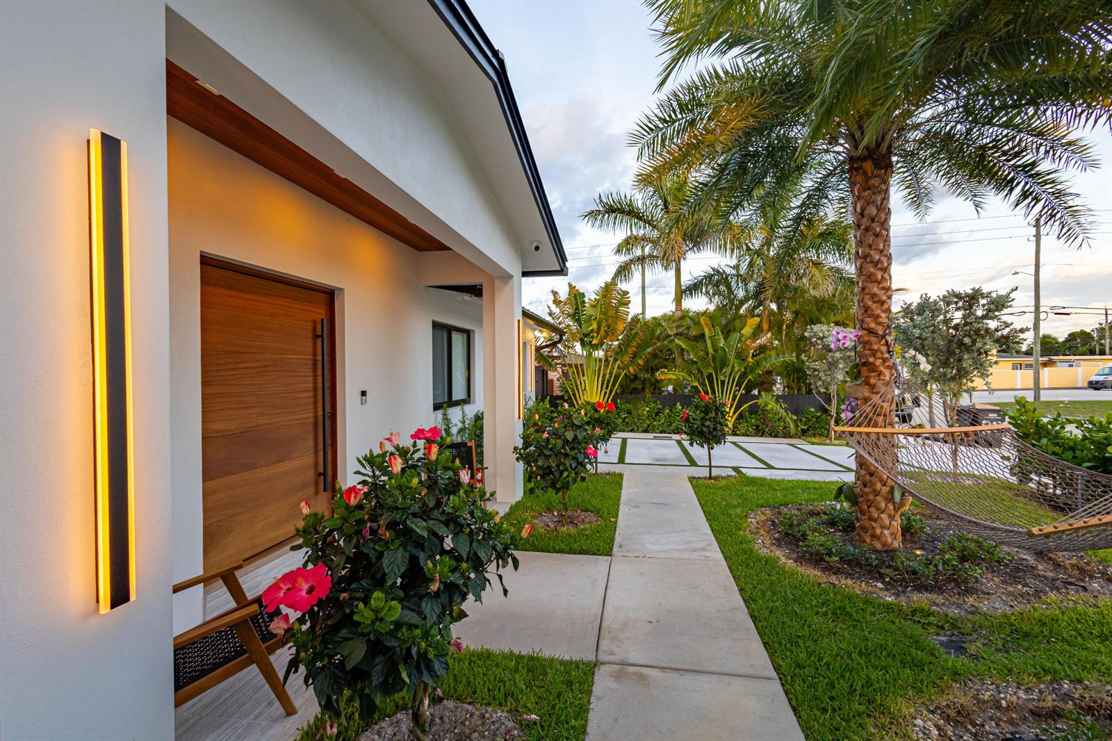 A modern home exterior features a wooden front door, vertical wall lighting, and a palm tree — 807 Hollywood Place, West Palm Beach FL 33405, WEST PALM BEACH, FL