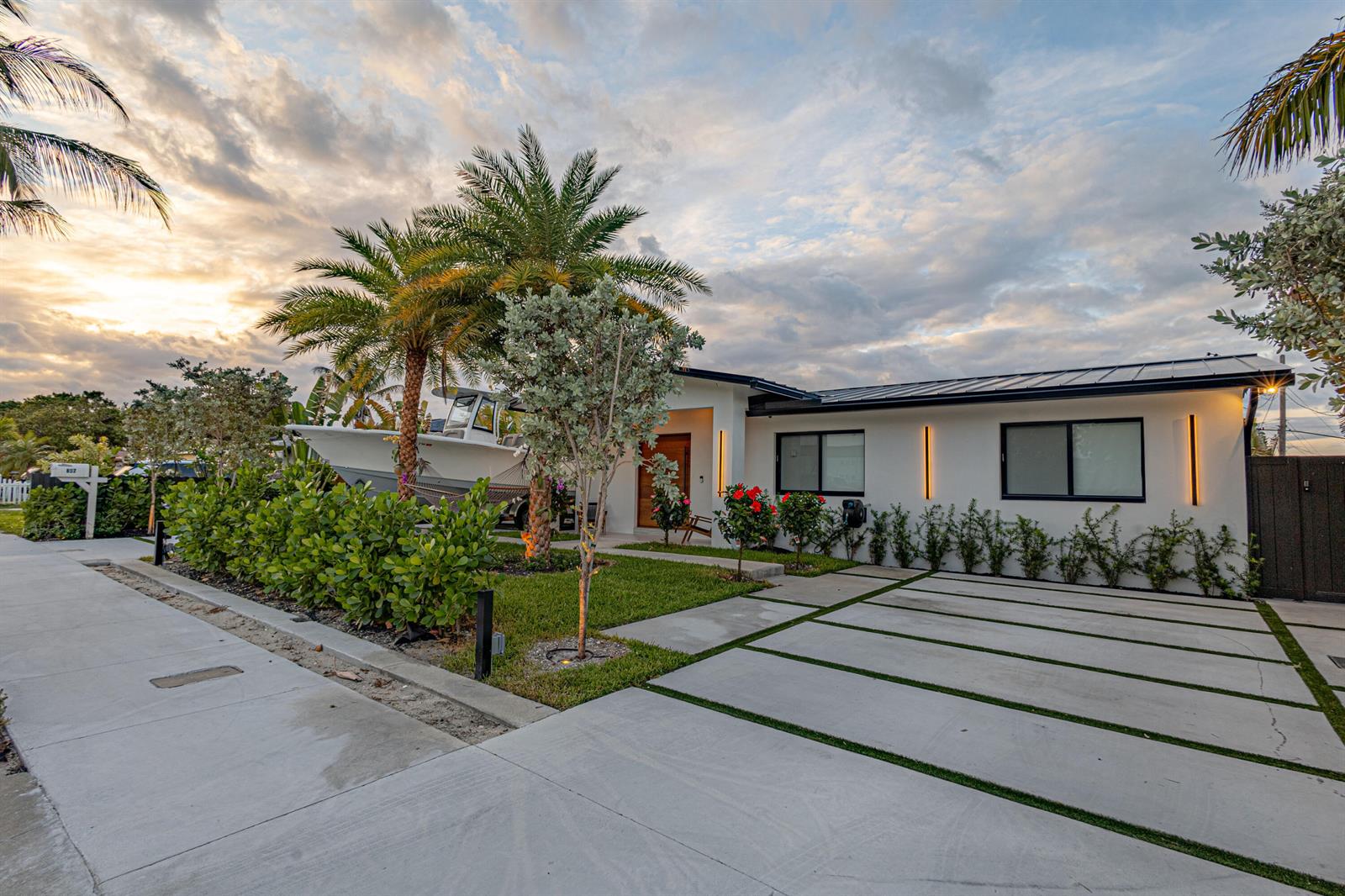 A modern white house with a boat parked in the front yard and a concrete driveway — 807 Hollywood Place, West Palm Beach FL 33405, WEST PALM BEACH, FL