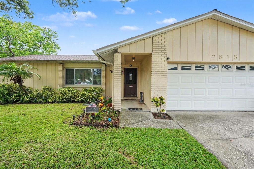 The exterior of a single-story house features beige siding, a brick entryway, and a garage — 2815 LINDEN TREE STREET, SEFFNER, FL