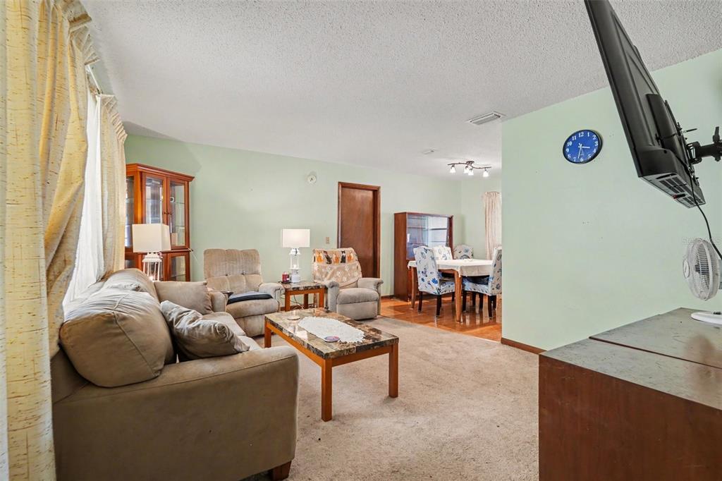 A living room with beige carpet, a sofa, two recliners, and an adjacent dining area — 2815 LINDEN TREE STREET, SEFFNER, FL