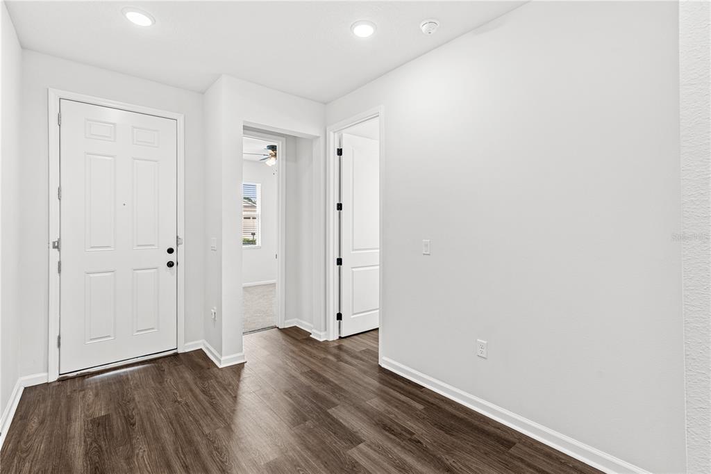 An entryway features a white front door, dark wood-look flooring, and two interior doorways — 10200 SPRING LAKE DRIVE, CLERMONT, FL