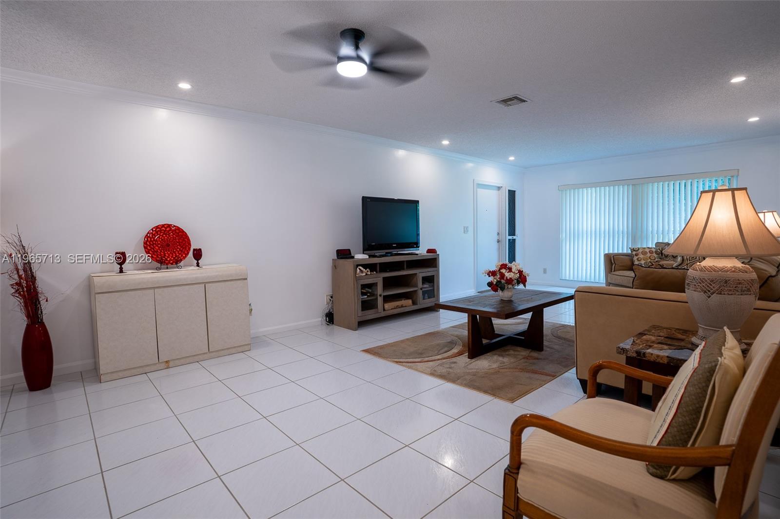 A living room features white tile floors, a ceiling fan, and a television console — 10198 DOVEWOOD LN # A, Boynton Beach FL 33436, BOYNTON BEACH, FL