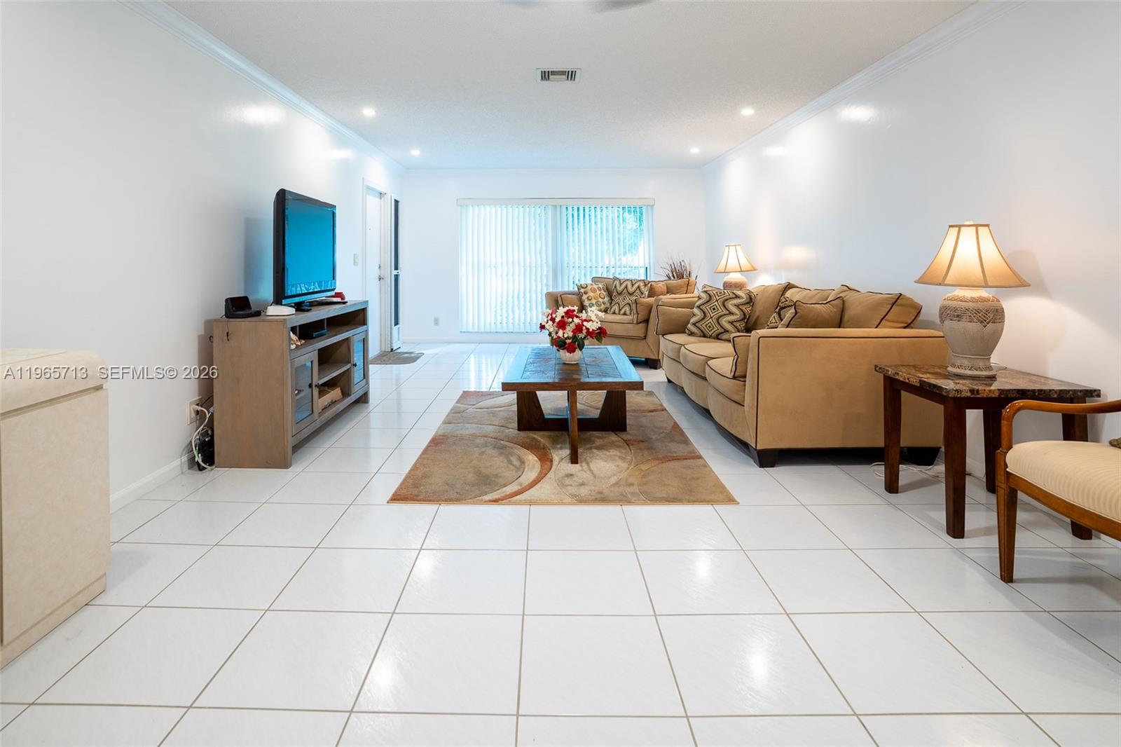 A living room features white tile flooring, a beige sofa, a coffee table, and a television — 10198 DOVEWOOD LN # A, Boynton Beach FL 33436, BOYNTON BEACH, FL