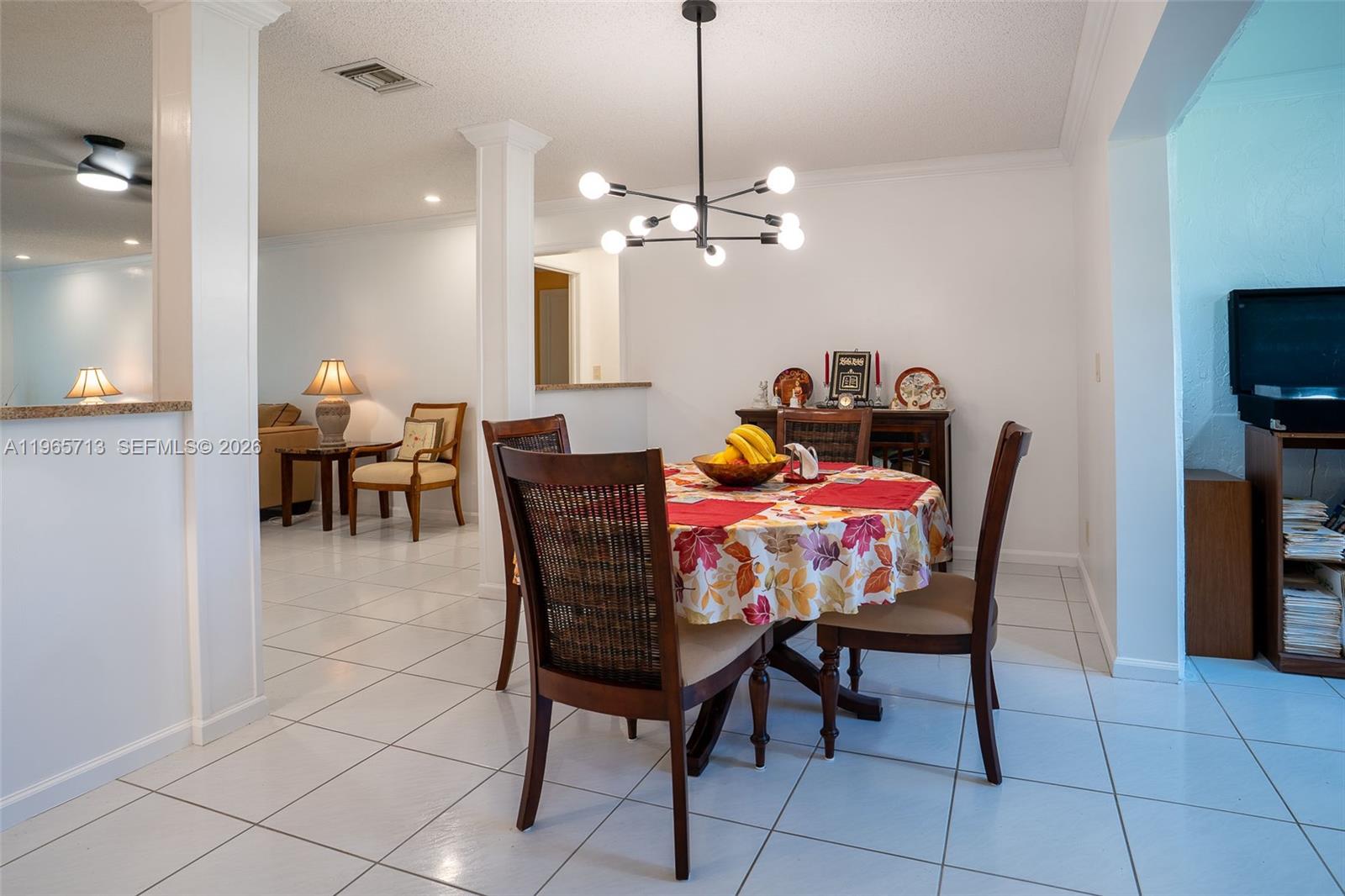 A dining area with a round table, wicker-back chairs, and a modern sputnik chandelier — 10198 DOVEWOOD LN # A, Boynton Beach FL 33436, BOYNTON BEACH, FL
