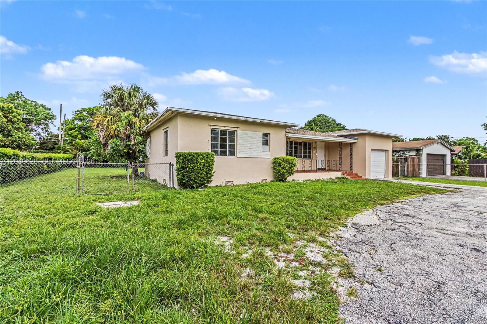 A single-story beige house with a front porch, attached garage, and a large grassy yard — 13020 NW 1st Ave # x, Miami FL 33168, MIAMI, FL