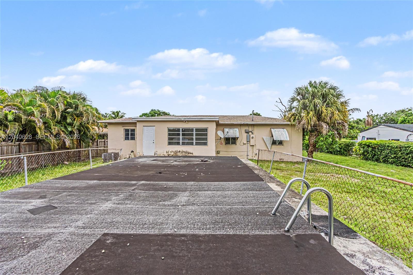 A backyard features a covered pool deck with a metal ladder and a beige house — 13020 NW 1st Ave # x, Miami FL 33168, MIAMI, FL