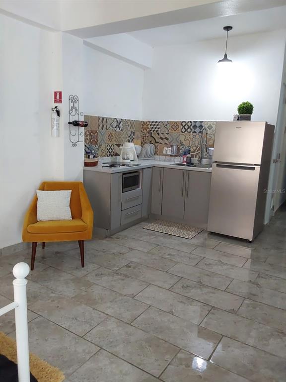 A small kitchen features gray cabinets, patterned tile backsplash, and a stainless steel refrigerator — 45 BARCELONA, GUAYAMA, PR