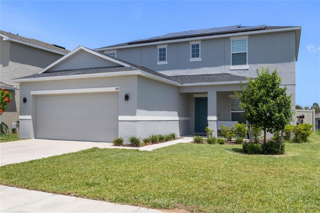 A two-story gray house features a two-car garage, a front porch, and solar panels — 470 HAMLET LOOP, DAVENPORT, FL