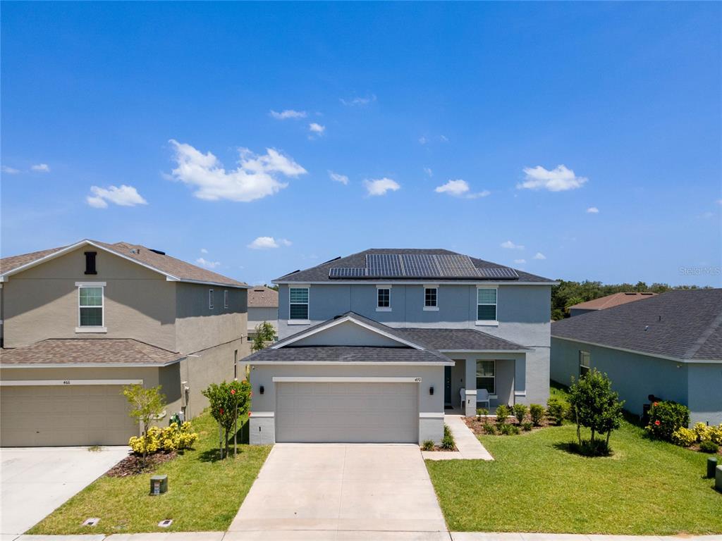 A two-story suburban house with a gray exterior, solar panels, and a two-car garage — 470 HAMLET LOOP, DAVENPORT, FL