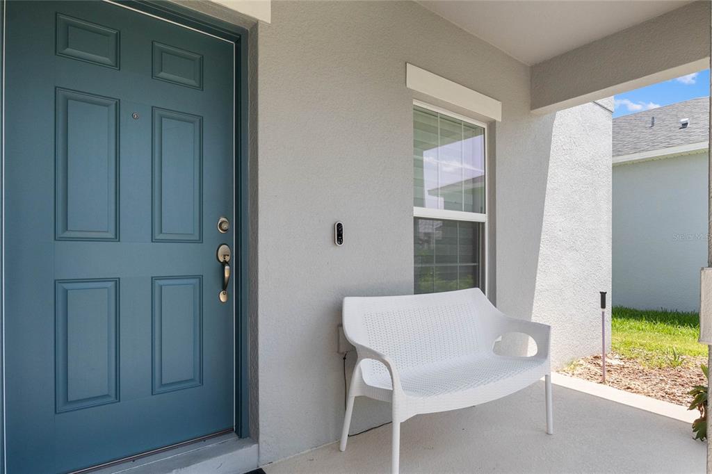 A blue front door and a white bench sit on a covered concrete porch — 470 HAMLET LOOP, DAVENPORT, FL