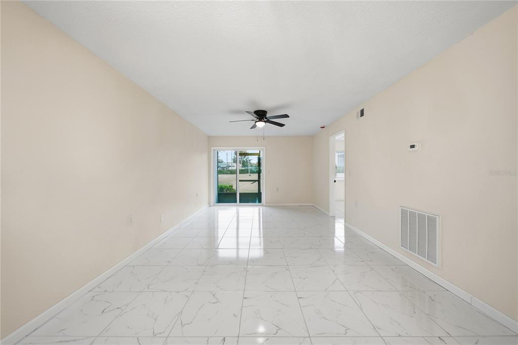 An empty room with white marble-look tile flooring, beige walls, and a ceiling fan — 39132 COUNTY ROAD 54 UNIT 2076, ZEPHYRHILLS, FL