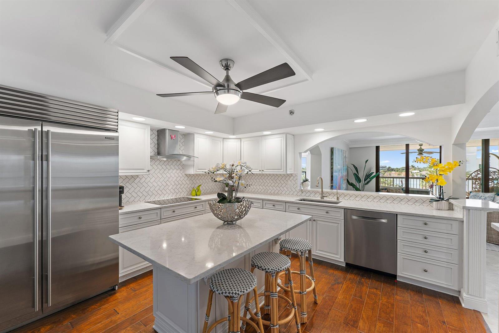 A bright kitchen features white cabinetry, a central island with bar stools, and stainless appliances — 19670 Beach Road # B303, Jupiter FL 33469, JUPITER, FL