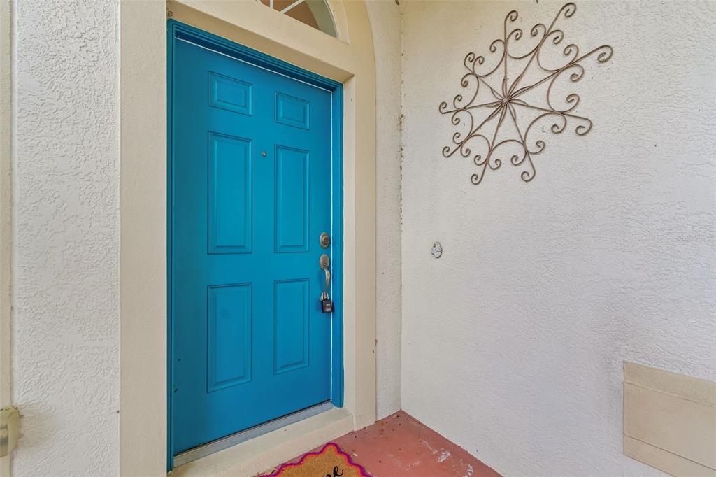 A bright blue front door with a lockbox is set against a white stucco wall — 4017 LANGDRUM DRIVE, WESLEY CHAPEL, FL