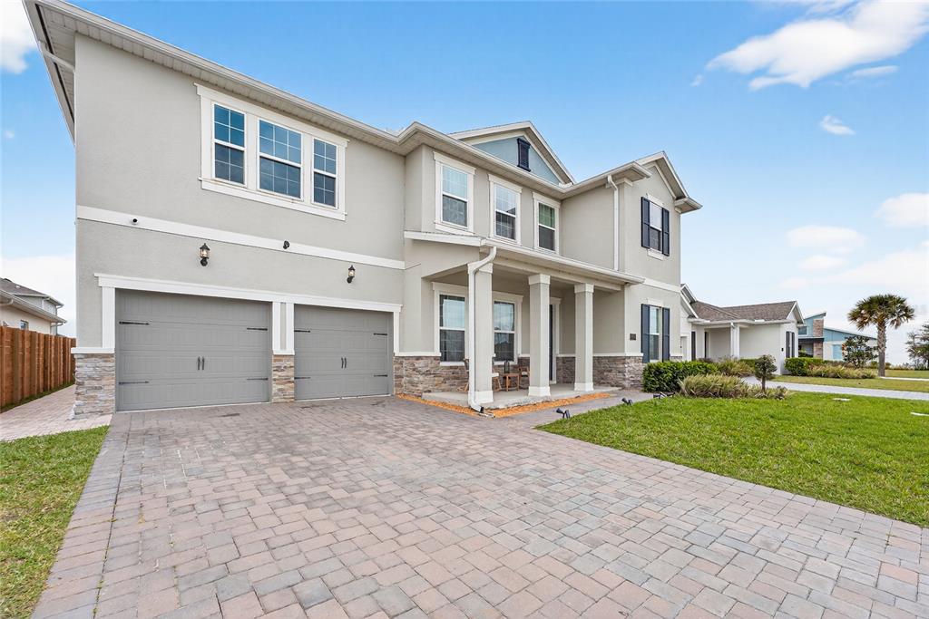 A two-story house with a gray stucco exterior, stone accents, and a paved driveway — 19076 PLANETREE STREET, ORLANDO, FL