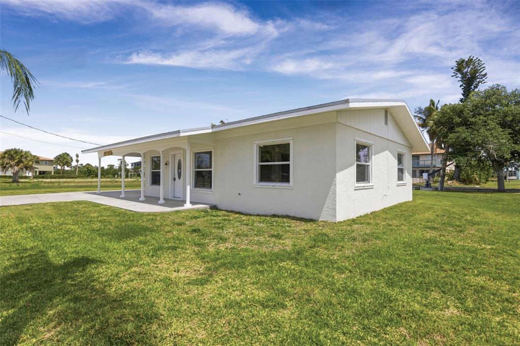 A white, single-story house with a covered front porch sits on a grassy lot — 10451 MARION STREET, ENGLEWOOD, FL