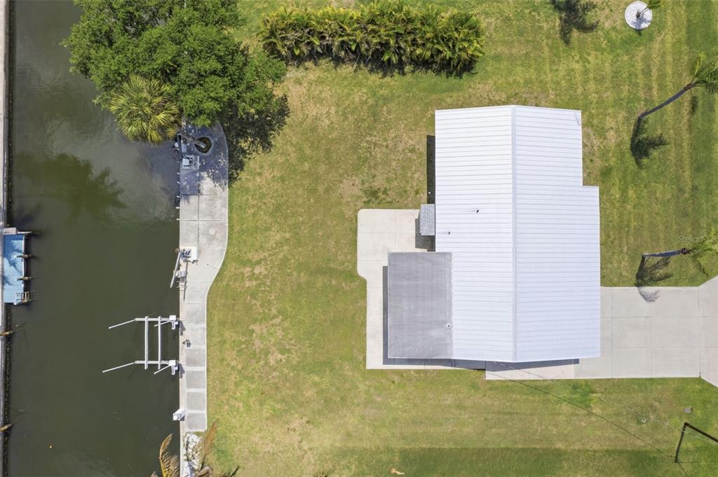 An aerial view shows a house with a white roof, a lawn, and a canal — 10451 MARION STREET, ENGLEWOOD, FL