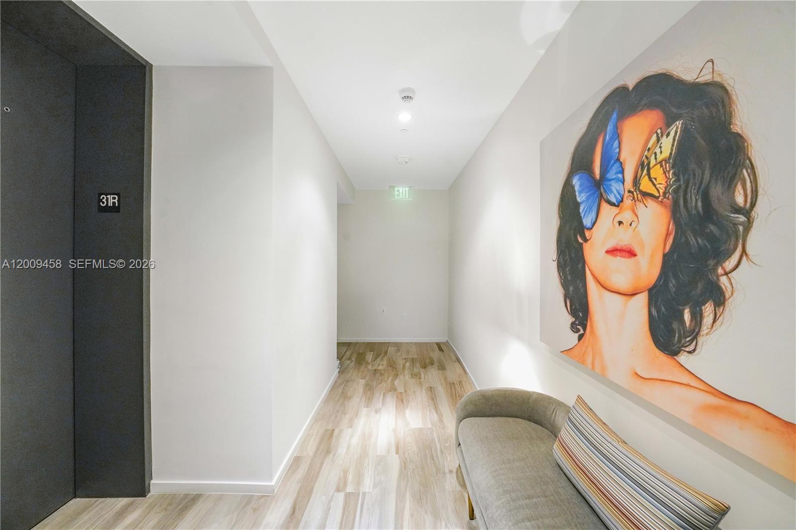 A hallway features wood-look flooring, a grey bench, and a large portrait of a woman — 801 S Miami Ave # 3109, Miami FL 33130, MIAMI, FL