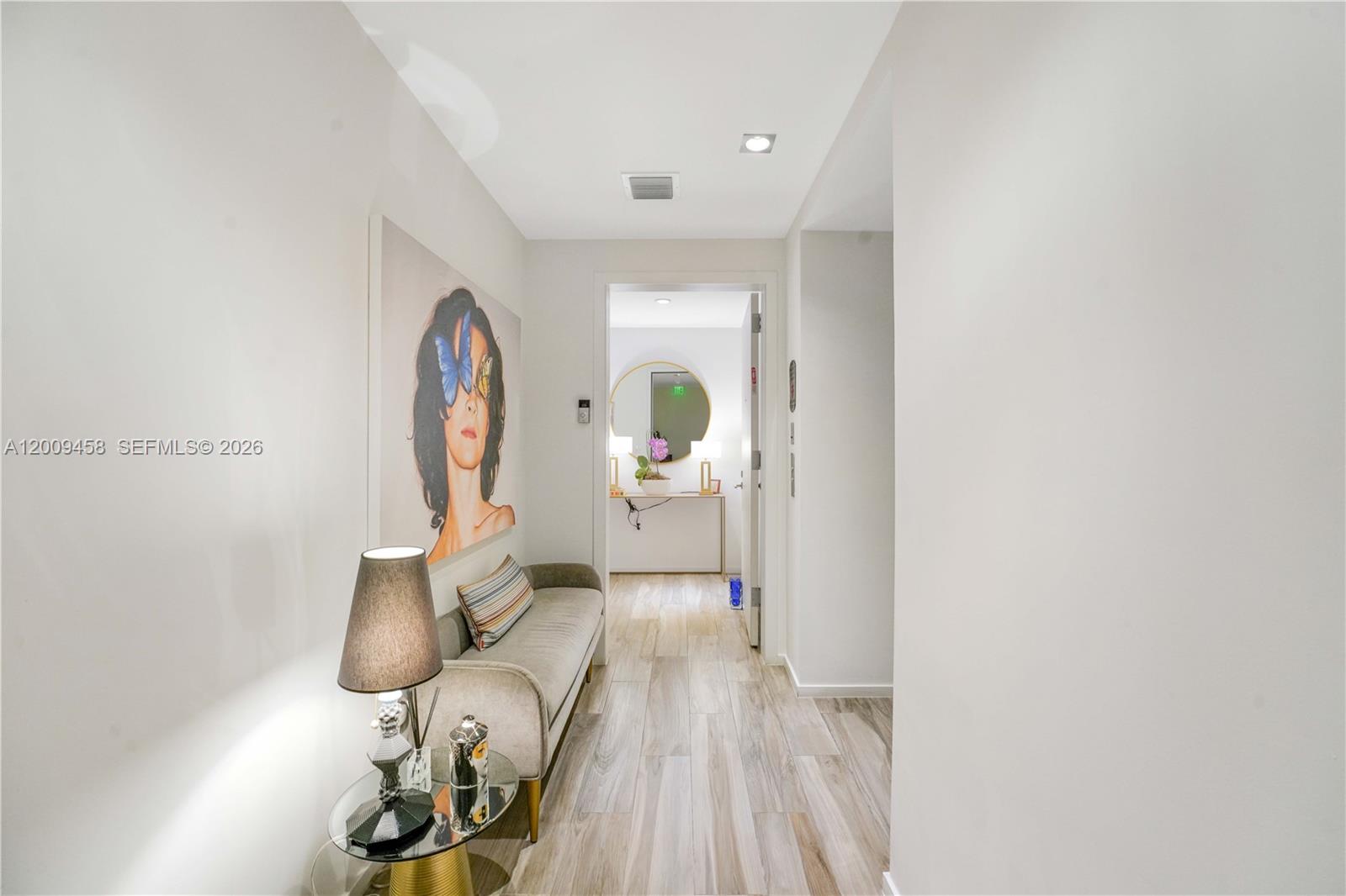 A hallway features light wood-look tile flooring, a gray bench, and a large portrait painting — 801 S Miami Ave # 3109, Miami FL 33130, MIAMI, FL