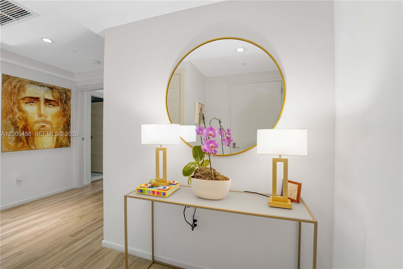 A console table with lamps and an orchid sits below a round gold-framed mirror — 801 S Miami Ave # 3109, Miami FL 33130, MIAMI, FL